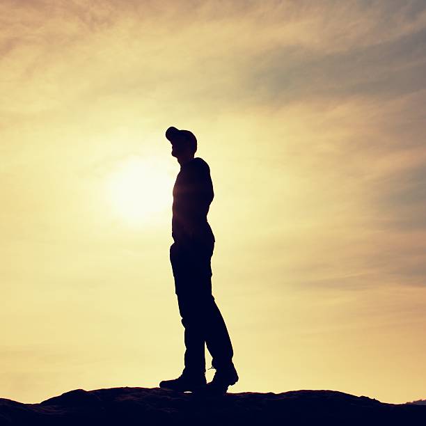 istock Silhouette human standing on rocky pedestal on nature daybreak  background. 514499054