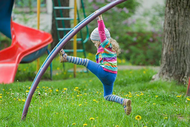 Active little girl is climbing monkey bar outdoors on spring playground
