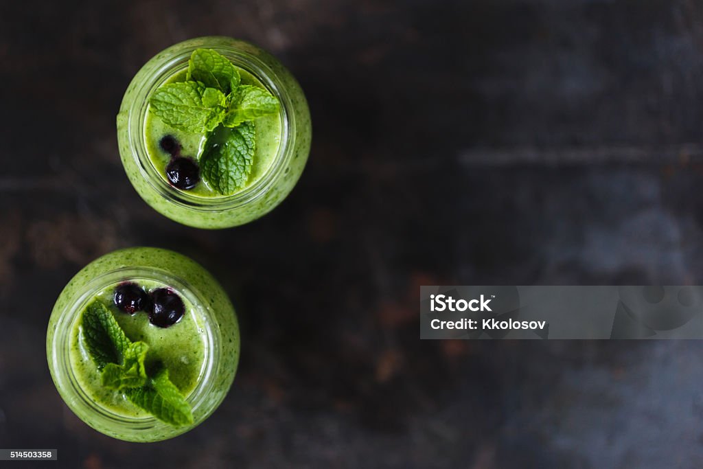 Two green smoothie in the jar Two green smoothie with banana and spinach, fresh herbs on the dark background, free copyspace for design,  top view Blended Drink Stock Photo