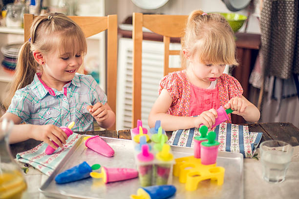 istock Two Little Girls Eating Popsicles at Home 514504576