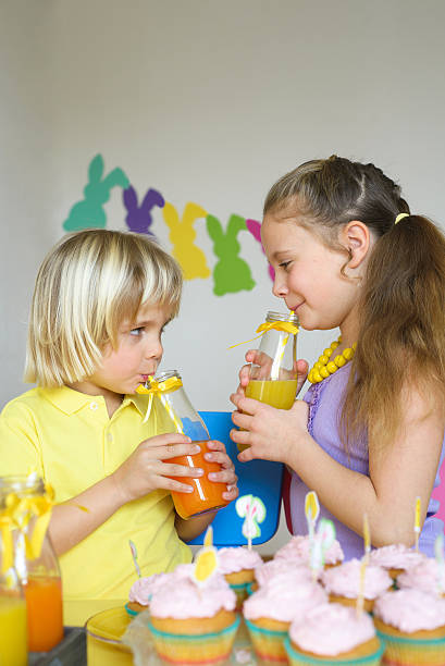 kinder trinkt orangensaft mit strohhalm in ostern-szene - child portrait fine art portrait multi colored stock-fotos und bilder