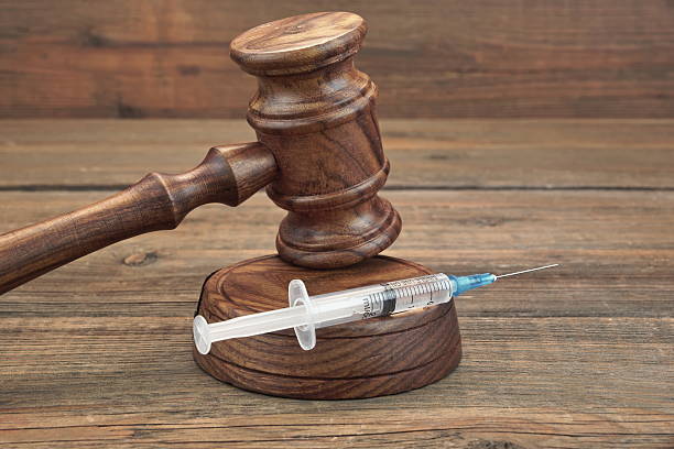 Judges Gavel And Syringe On Brown Wooden Background Close-up stock photo