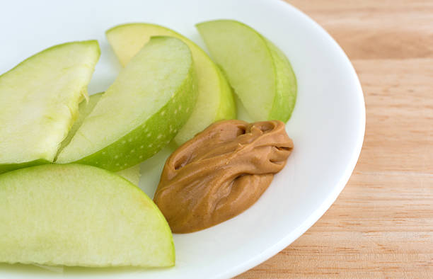 istock Green apple slices on dish with peanut butter table top 514508218