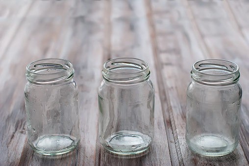 three empty small jars for yogurt on a wooden table
