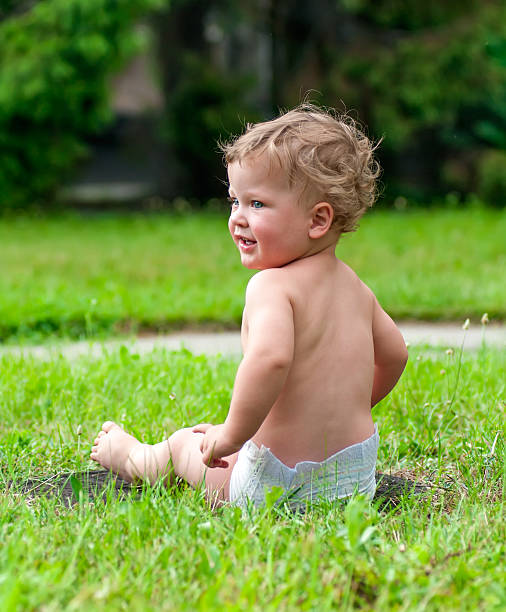 istock little curly-headed child is sitting on the green grass 514512989