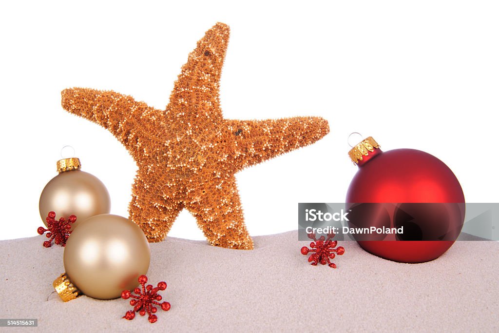 Holiday In The Sand Holiday ornaments and a starfish in sand on a white background with copy space for your special Holiday text. Christmas Stock Photo