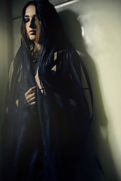 istock woman in a black robe at green wall 514518532