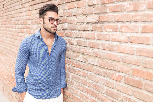 istock casual young man leaning against brick wall 514520643