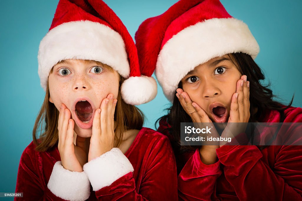 Santa's Little Helpers With Surprised/Shocked Look on Their Faces Color image of two little girl friends wearing Santa hats and looking shocked/surprised/stressed. 8-9 Years Stock Photo