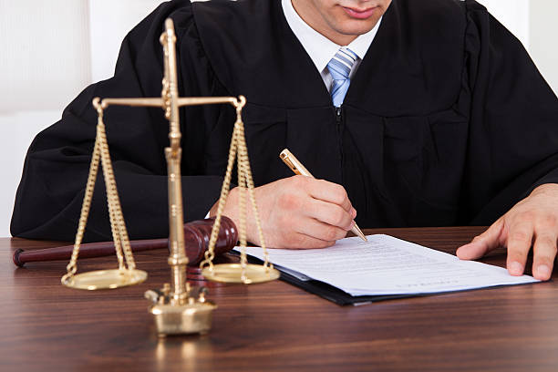 istock Judge Signing Document At Table In Courtroom 514536445