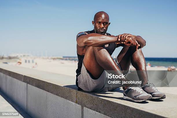 Fit Young Athlete Relaxing On Sea Wall After Workout Stock Photo - Download Image Now