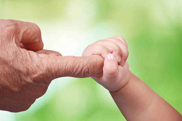 Elderly and Baby Close up image of baby's hand holding elderly's finger old man baby stock pictures, royalty-free photos & images