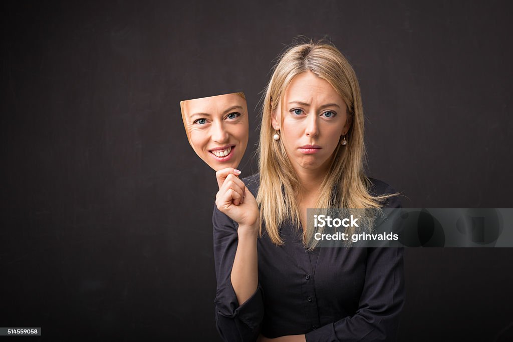 Woman holding mask of her happy face Artificial Stock Photo