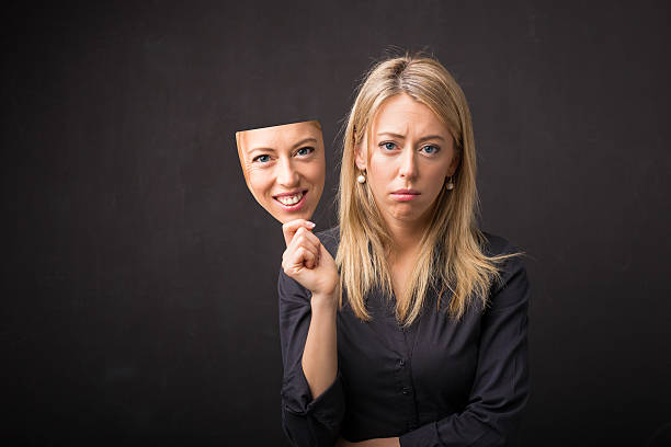 Woman holding mask of her happy face Woman holding mask of her happy face mask disguise stock pictures, royalty-free photos & images