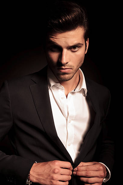 istock fashion man buttoning his suit on black background 514560357