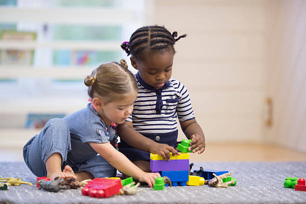 Learning How to Share A multi-ethnic group of preschoolers are playing with plastic blocks together in class. toddler stock pictures, royalty-free photos & images