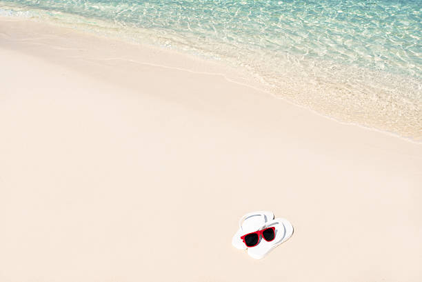 istock White Flip flops and sunglasses at the sandy beach 514563602