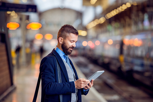 Inconformista hombre de negocios con tableta, en espera, plataforma de tren photo