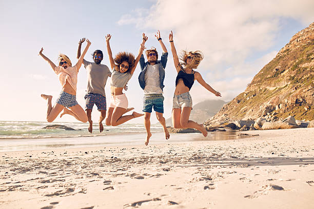 grupo de amigos divirtiéndose en la playa - jumping freedom women beach fotografías e imágenes de stock