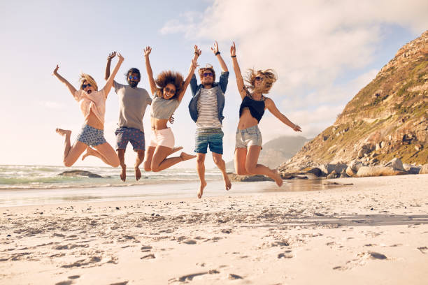 grupo de amigos na praia a divertir-se - ecstatic excitement arms raised men imagens e fotografias de stock