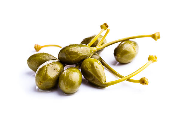 canned capers on white reflective background canned capers isolated on a white reflective background caper stock pictures, royalty-free photos & images