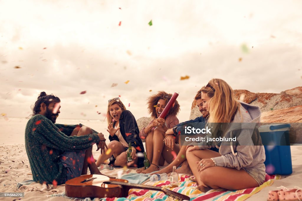 Best friends at beach party Happy friends partying on the beach with drinks and confetti. Happy young people having fun at beach party, celebrating with confetti. Beach Party Stock Photo