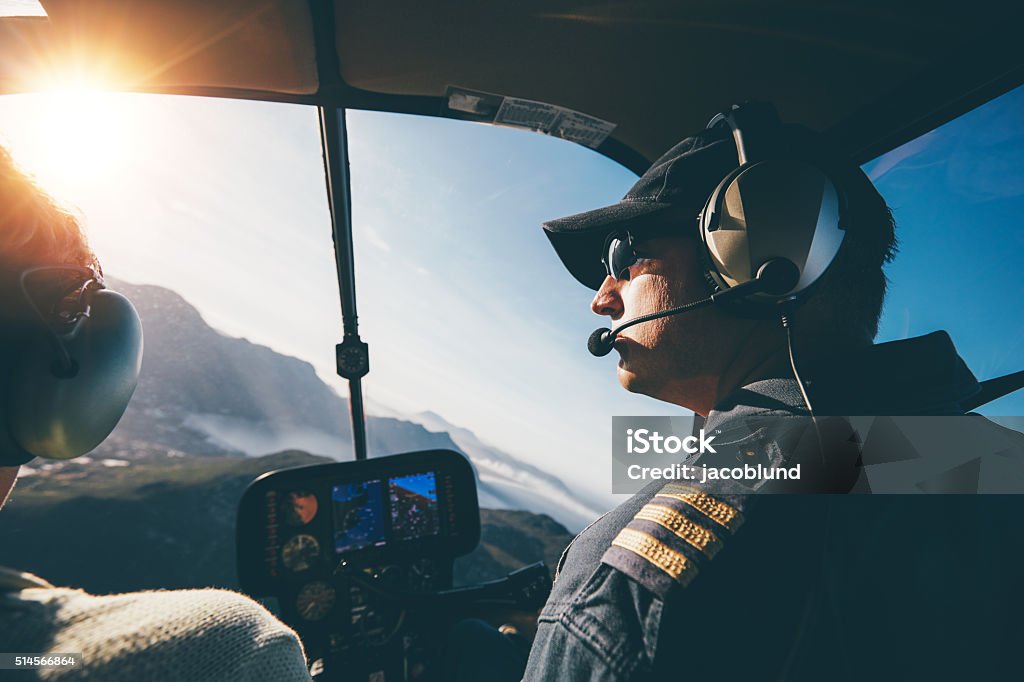 Flying a helicopter on a sunny day Man and woman pilots flying a helicopter on a sunny day. Inside shot of a helicopter. Helicopter Pilot Stock Photo