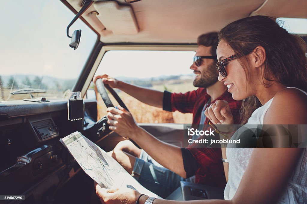 Young couple using a map on a roadtrip for directions Side view of young couple using a map on a roadtrip for directions. Young man and woman reading a map while sitting in a car. Car Stock Photo