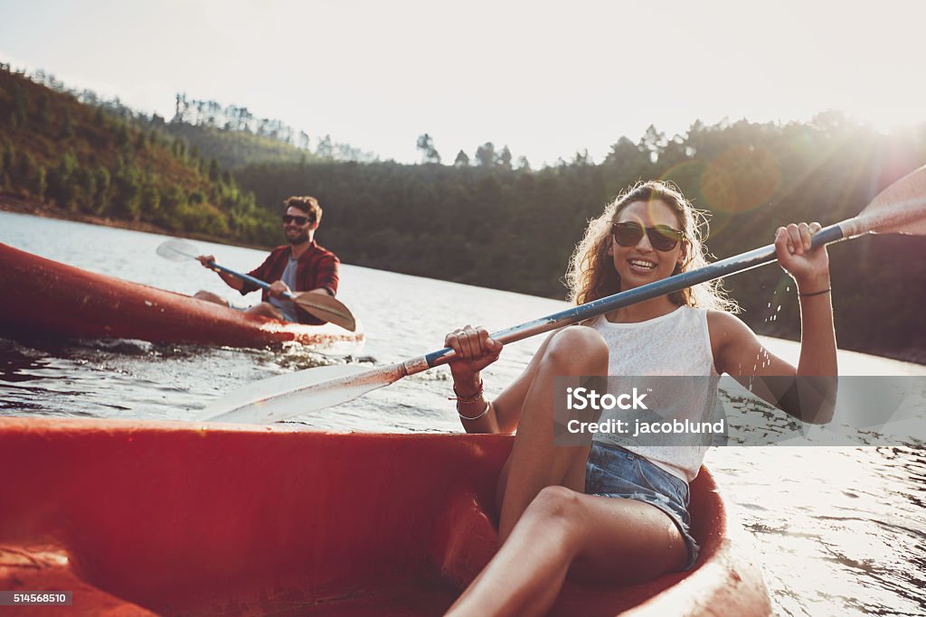 Young people canoeing in a lake Beautiful young woman kayaking in a lake with man paddling in the background. Young couple canoeing on summer day. Kayak Stock Photo