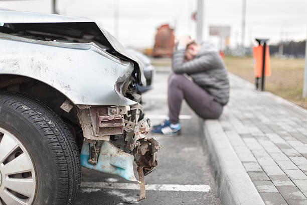 broken car after the accident in  foreground broken  gray car after the accident in  the foreground, brokenness metal parts, in the background a man telephoned the service Desk road accident stock pictures, royalty-free photos & images
