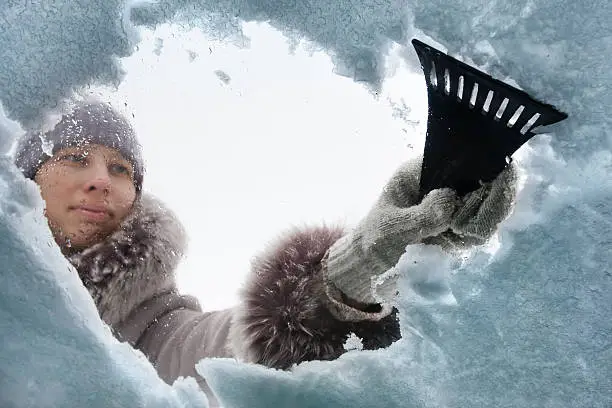 Photo of woman cleaning window of car from the snow with scraper