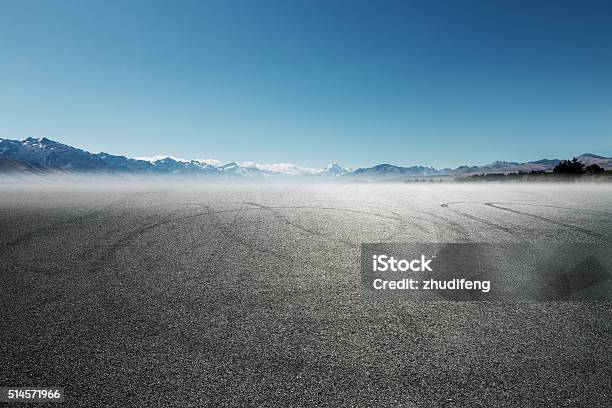 Empty Asphalt Road With Car Tracks With Snow Mountains Stock Photo - Download Image Now