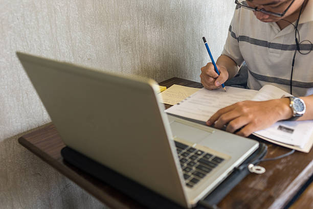 Student listenning English lessons on laptop and answer into book stock photo