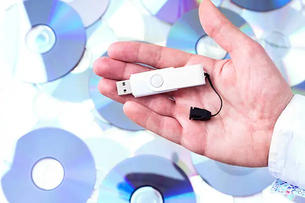 Photo of Man's hand with pendrive over CD's background.