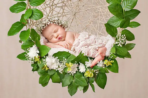 Photo of Little newborn girl 11 days, sleeps. Beautiful newborn and flowers