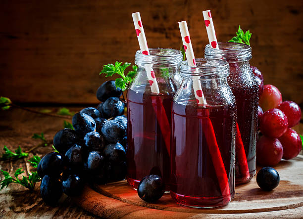 istock Dark grape juice in glass bottles with straws 514582532