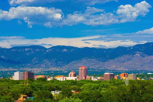 Albuquerque downtown skyline with the Sandia Mountains and clouds in the background.