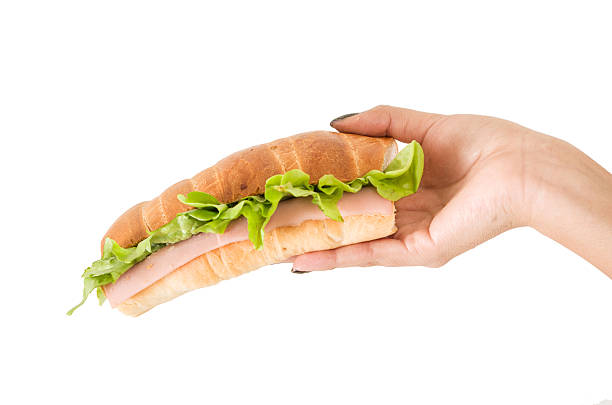 istock Closeup of hand holding lettuce and ham sandwich 514589059