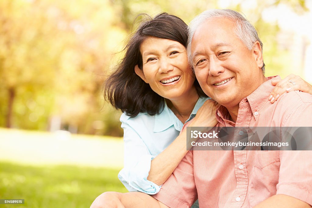 Portrait Of Senior Asian Couple Sitting In Park Together Portrait Of Senior Asian Couple Sitting In Park Together Smiling To Camera Senior Couple Stock Photo