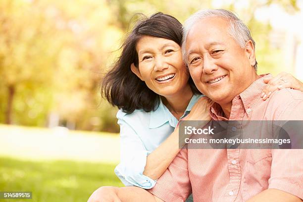 Portrait Of Senior Asian Couple Sitting In Park Together Stock Photo - Download Image Now