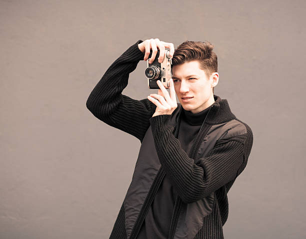 istock Man Photographs Model the Vintage Camera at a wall 514590177