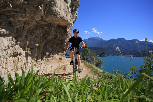 A mountainbiker on a trail nearby the village of Riva del Garda, Lake Garda, Italy. The lake is one of the best biking destinations in Europe with more than one thousand kilometres of waymarked trails for all abilities, breathtaking scenery and unparalleled natural beauty included.