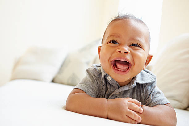 Laughing Baby Boy Lying On Tummy At Home Laughing Baby Boy Lying On Tummy At Home Looking Ahead cute baby laughing stock pictures, royalty-free photos & images