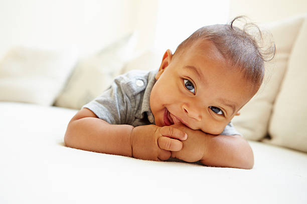 sonriente bebé niño acostado de estómago en su hogar - baby cute laughing human face fotografías e imágenes de stock