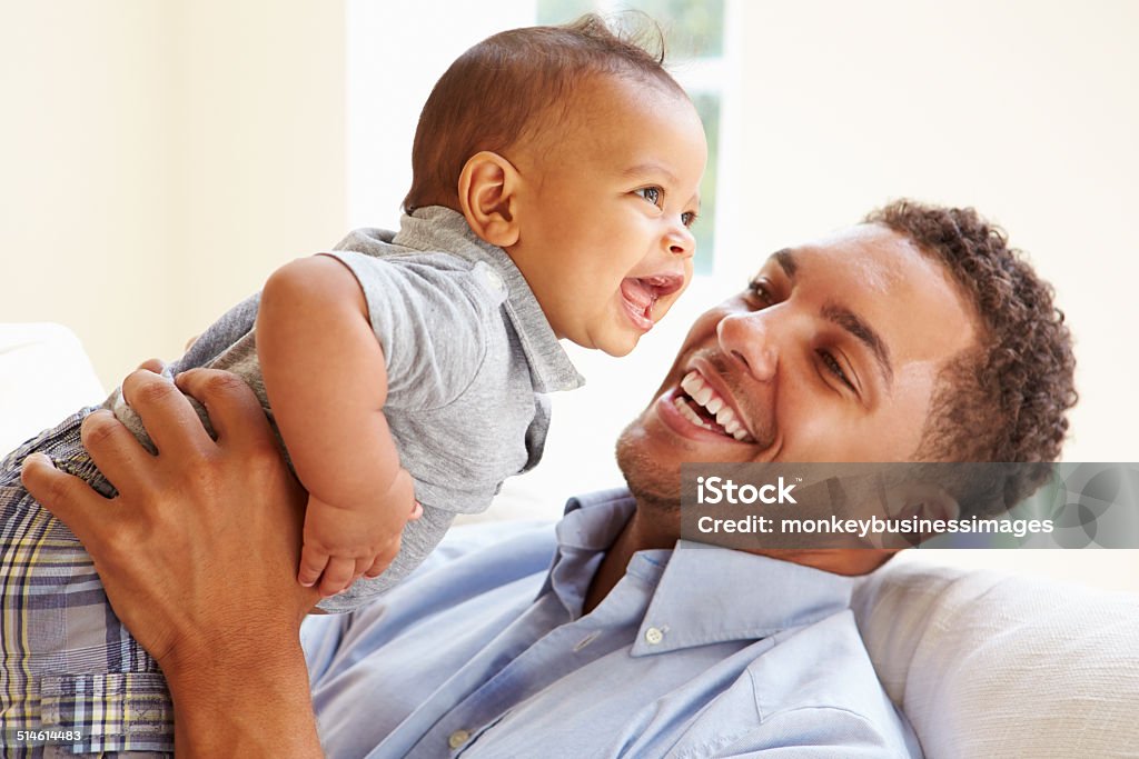 Smiling Father Playing With Baby Son At Home Smiling Father Playing With Baby Son At Home Lifting Up Baby - Human Age Stock Photo