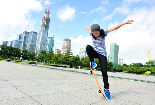 skateboarding  woman jumping at city
