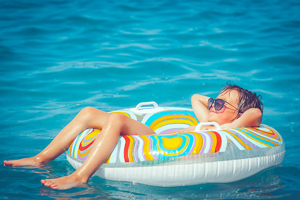 Child in the sea Happy little boy having fun in the sea inner tube stock pictures, royalty-free photos & images