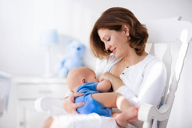 bonito jovem mãe com bebê menino em casa - breastfeeding newborn mother baby - fotografias e filmes do acervo