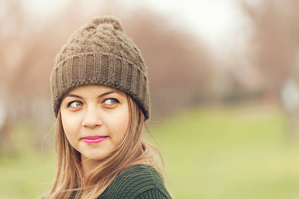outdoors portrait of beautiful girl in hat on the background of a large tree.