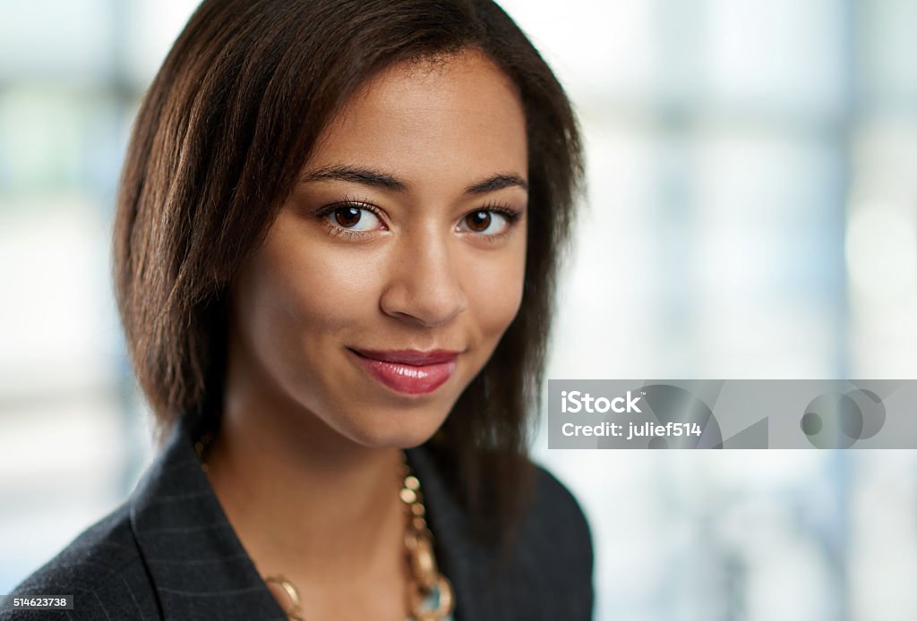 Horizontal headshot of an attractive african american business woman shot Portrait of a confident young mixed-raced female employee part of a business team. Serie shot with a pastel, out of focus glass window background. Professional Occupation Stock Photo